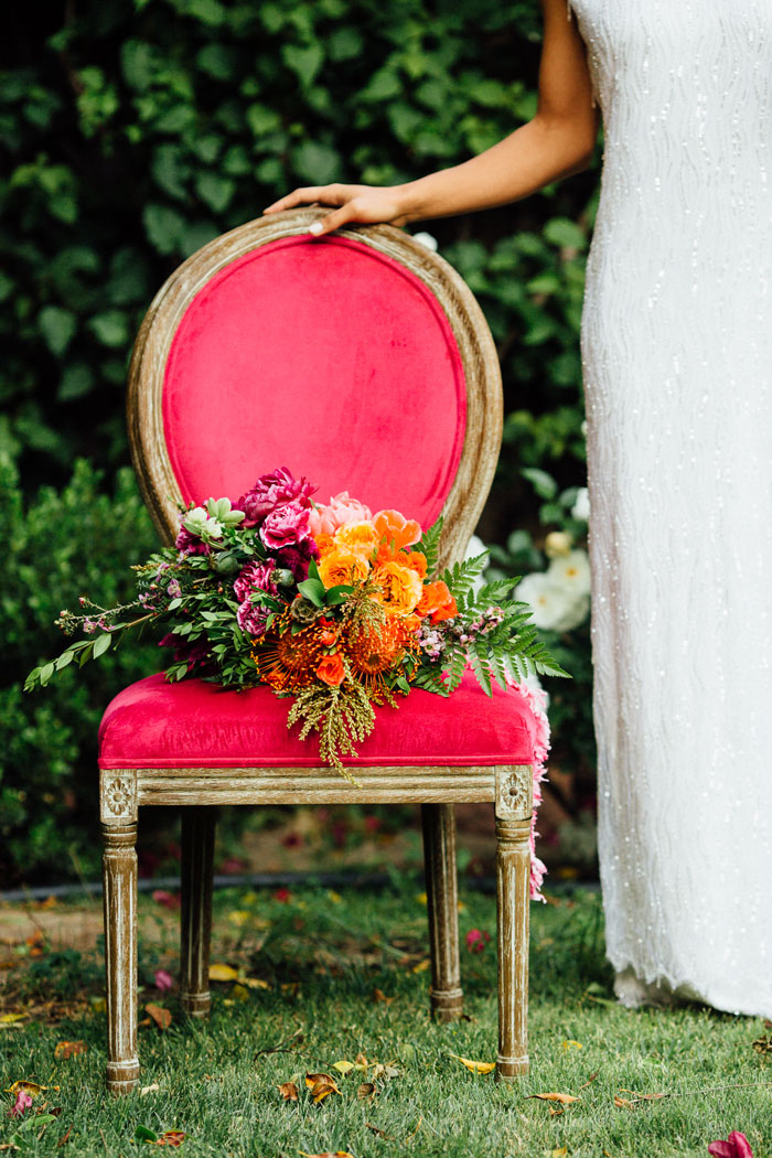 Colorful bridal bouquet resting on beautiful pink vintage chair.