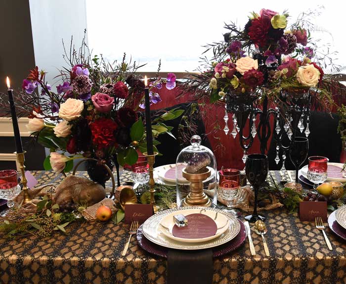 Halloween tablescape featuring dark florals, black tapers, and curious oddities.