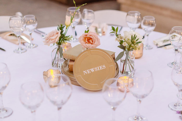 Romantic DTLA Library Wedding with centerpieces featuring garden roses, vintage books and film reel table names.