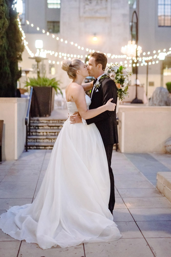 Couple kissing under cafe lights at romantic DTLA library wedding