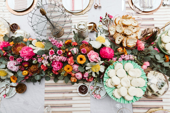 A birds-eye-view of a lush early summer floral garland on a table set for afternoon tea.