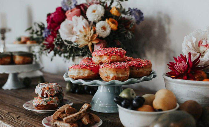 Decadent wedding spread including lush floral arrangement and delicious donuts.