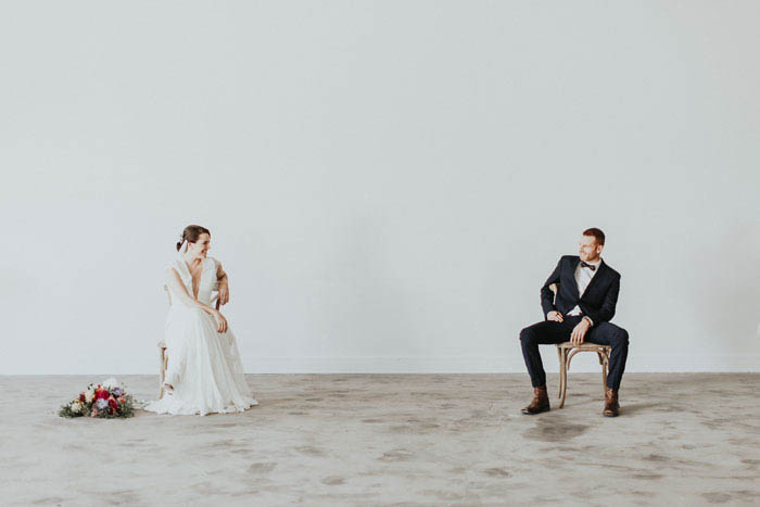 Sophisticated wedding portrait- cute couple sitting on rustic chairs.