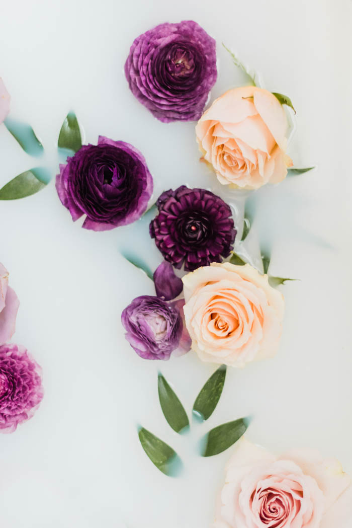 Purple ranunculus, peach roses, and italian ruscus milk bath photography