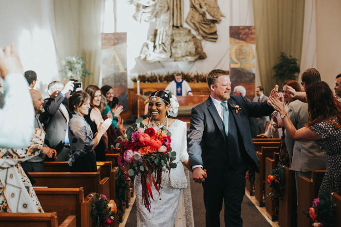 The cutest couple exit the church after their colorful wedding!