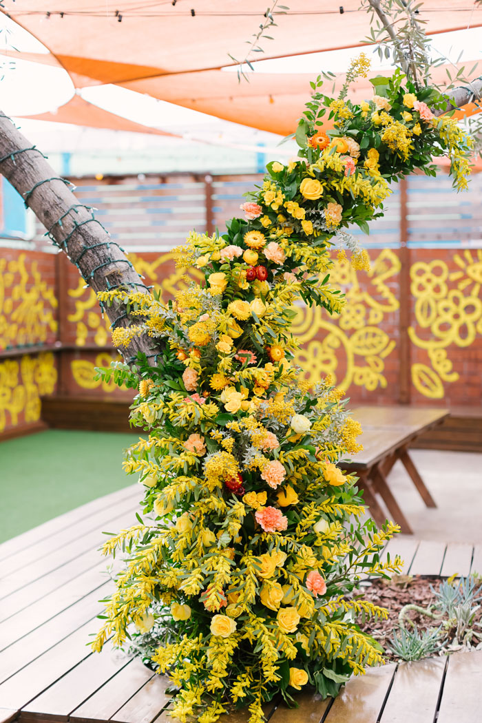 A brilliant foam-free floral installation climbs up a tree in the center of the reception space.