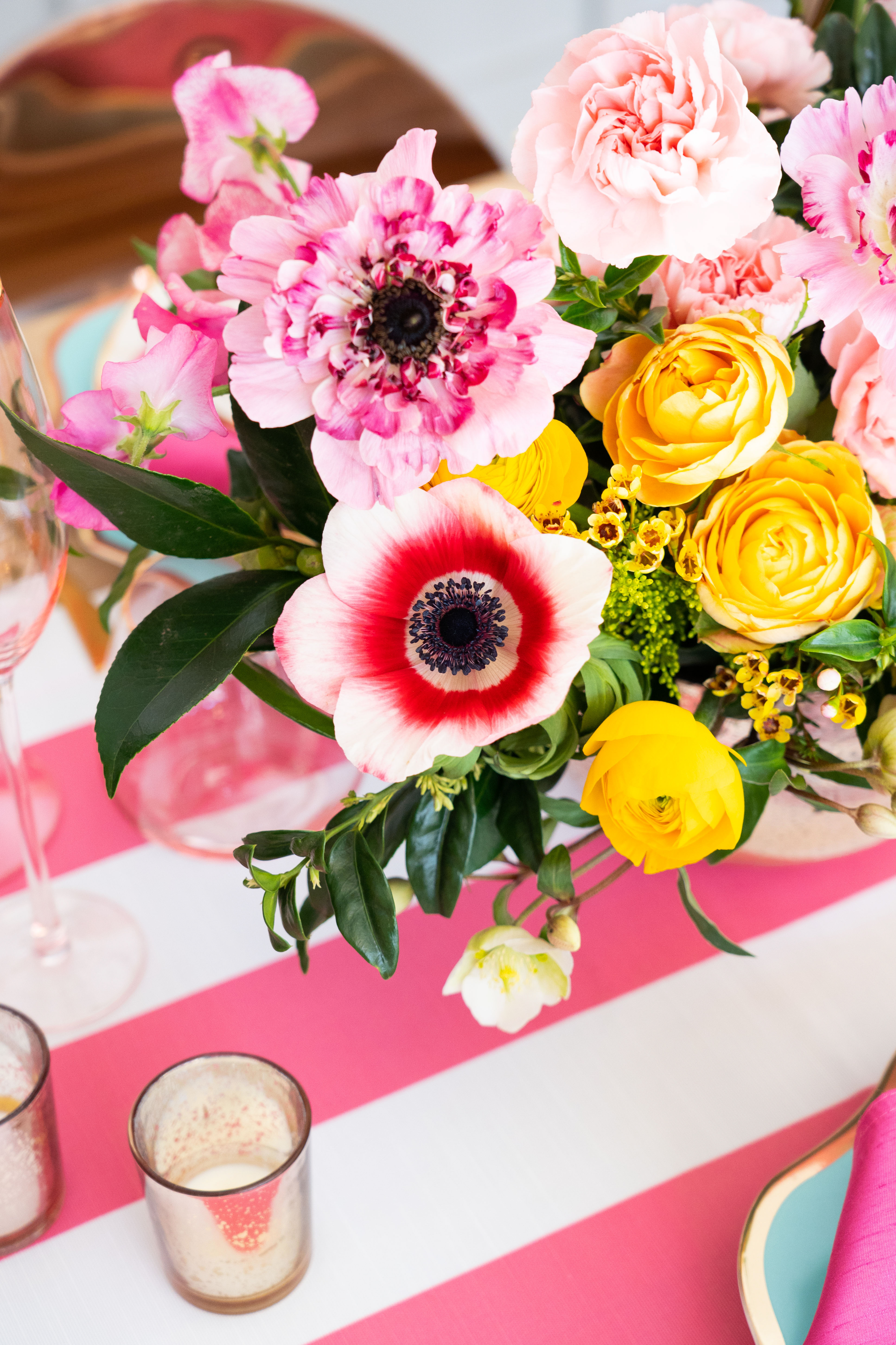 Vibrant pink and yellow reception table arrangements featuring ranunculus, anemones, and peonies by Winston and Main. 
