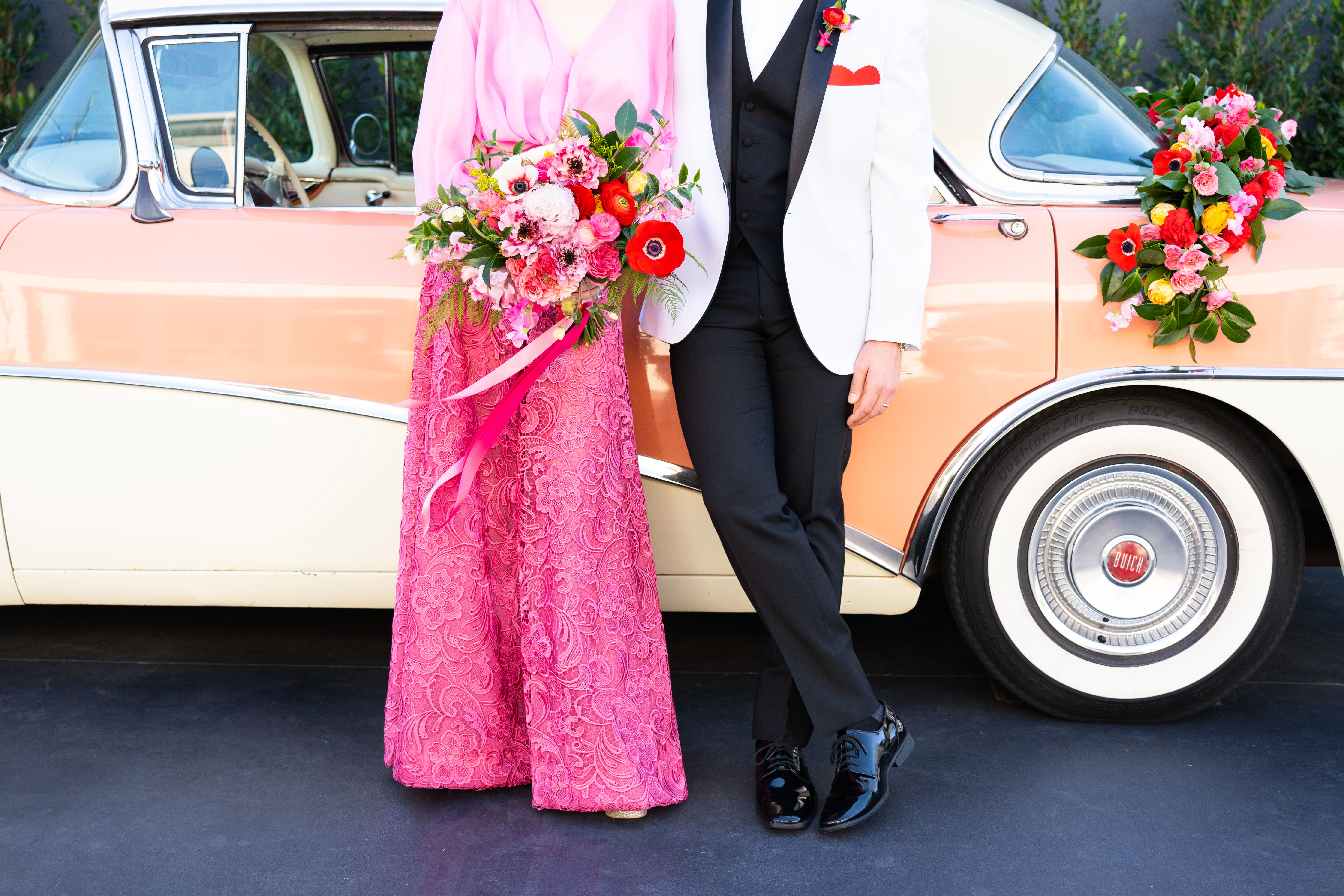 Our quirky sweet Valentine's Day couple wearing retro wedding attire to match their vintage getaway car adorned with a lush red and pink garland by Winston and Main.
