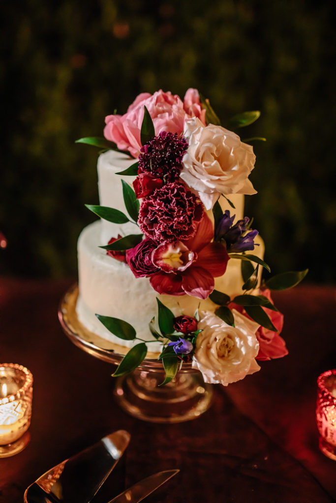 A romantic floral wedding cake with lush pink and red flowers decorated by florist Winston and Main