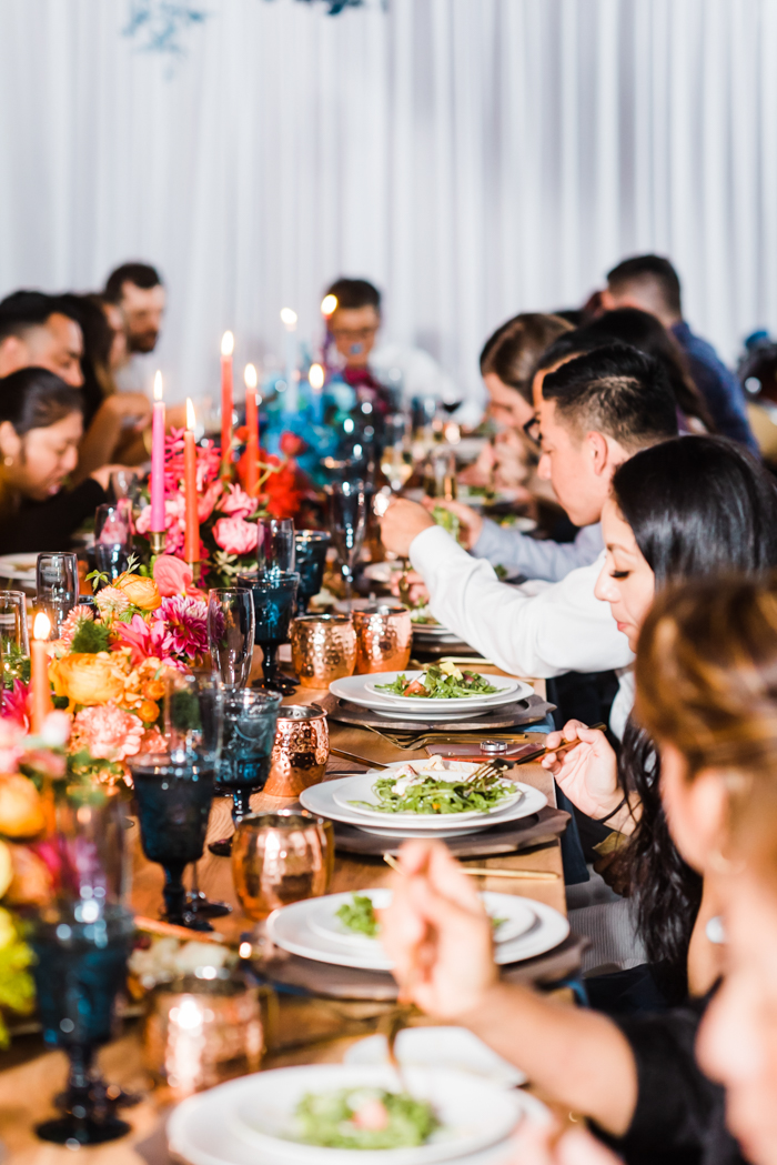 A wildly colorful dinner party with brightly colored ombre candles and florals down the length of the table.