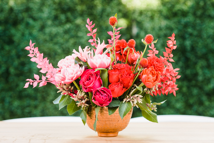 Bold pink and red floral arrangement featuring double tulips, clover, dahlias, and painted italian ruscus by Winston & Main