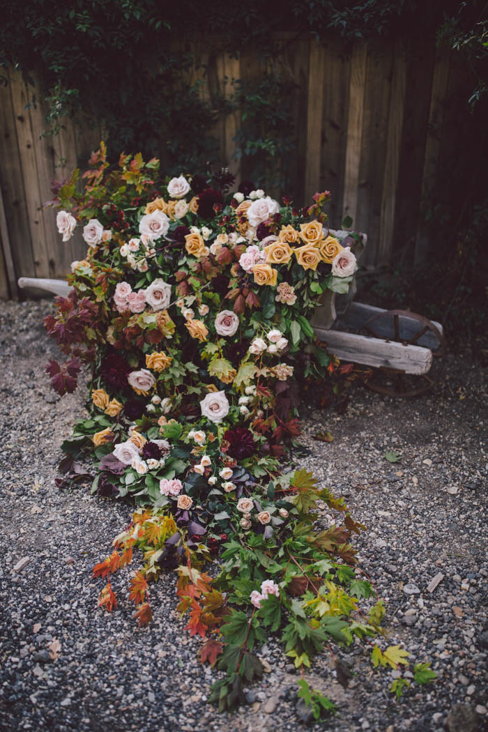 Lush and elegant fall flowers and foliage cascading from a vintage wheelbarrow.