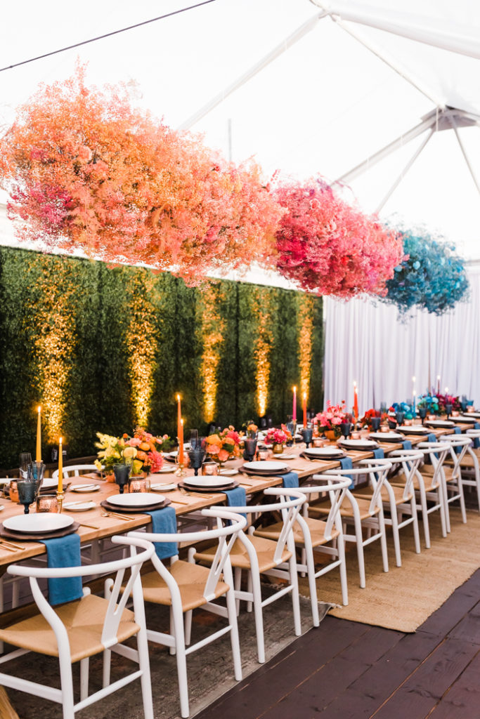 Bright and foam free floral clouds of dyed baby's breathe hanging over table of ombre floral arrangements.