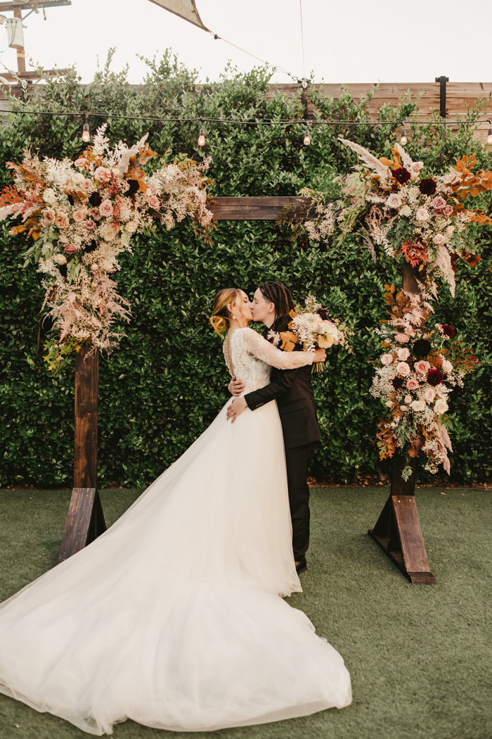 Light and airy foam free floral arch featuring blush, nude, and neutral flowers, fall leaves, baby's breath, and burgundy dahlias.