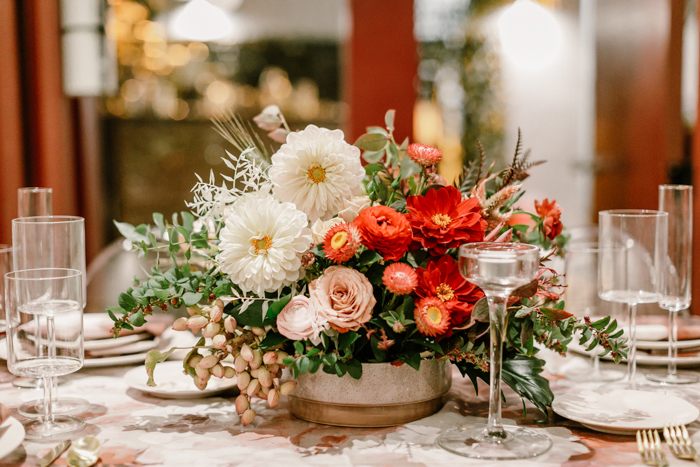 Beautiful red ombre centerpiece featuring dahlias, ranunculus, cappuccino roses, and strawflower by Winston & Main