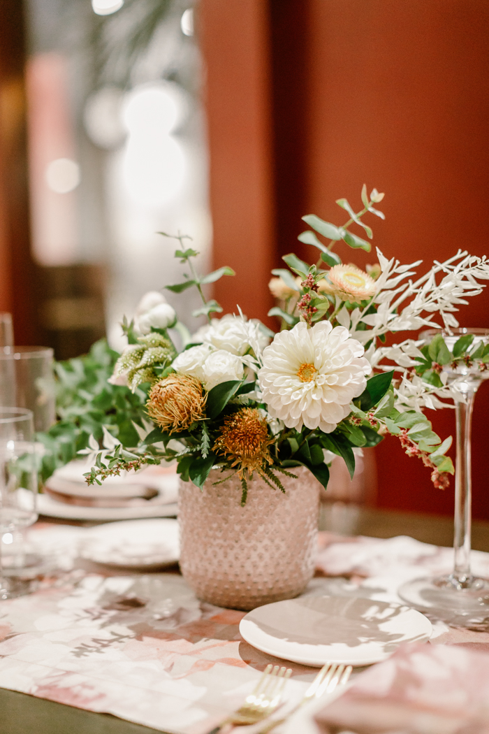 An organic floral arrangement featuring white dahlias, strawflowers, and banksia by Tabitha Abercrombie of Winston & Main. 