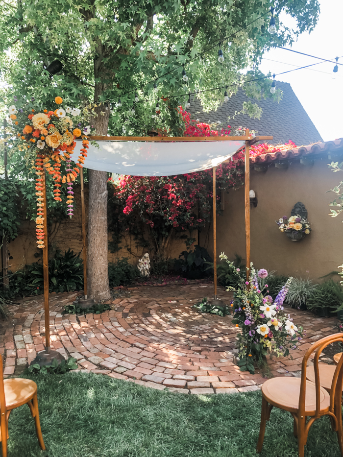 A whimsical monochromatic Chuppah installation featuring peonies, poppies, marigold, and carnation garland.