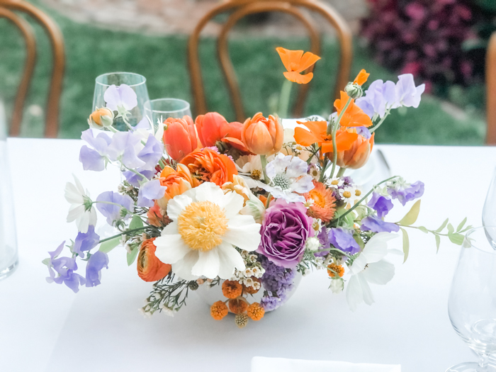 A signature Winston & Main centerpiece- it's loose, airy, and organic and features peonies, garden roses, sweet pea, ranunculus, california poppies, and more in a low vessel with very little greenery.