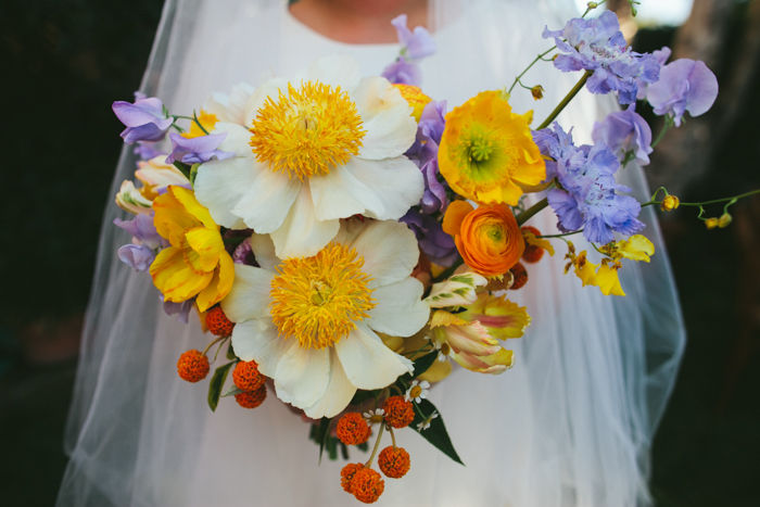 A beautiful spring bouquet by Winston & Main featuring Claire De Lune Peonies, Poppies, and whimsical accent blooms in shades of lavender, orange, & yellow.