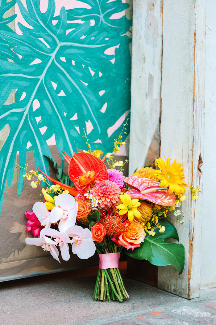 Our colorful, tropical wedding bouquet is full of unique, luxe, and textural flowers in shades of pink, orange, yellow, and red.
