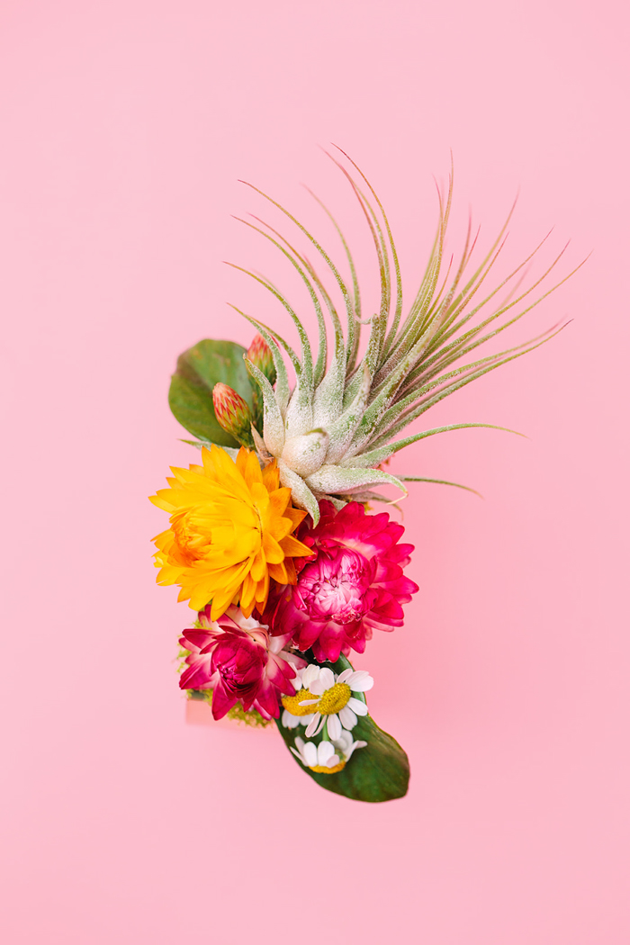 A cool & modern signature Winston & Main cuff corsage featuring an air plant and colorful pink & yellow strawflowers.