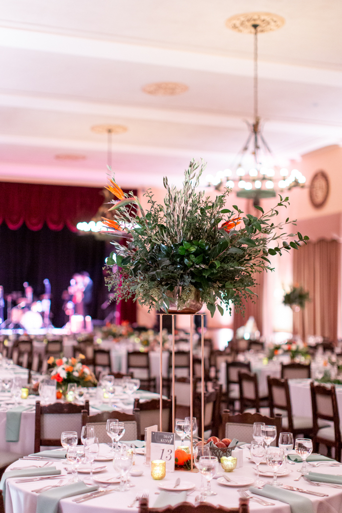 A tall centerpiece both wild & composed, is full of textural olive and eucalyptus, and has bird of paradise accents blooms.