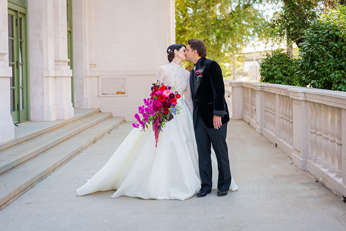 The couple sharing a kiss on the steps of the Ebell, and the bride holding a bright luxury bouquet designed by Tabitha Abercrombie of Winston & Main.