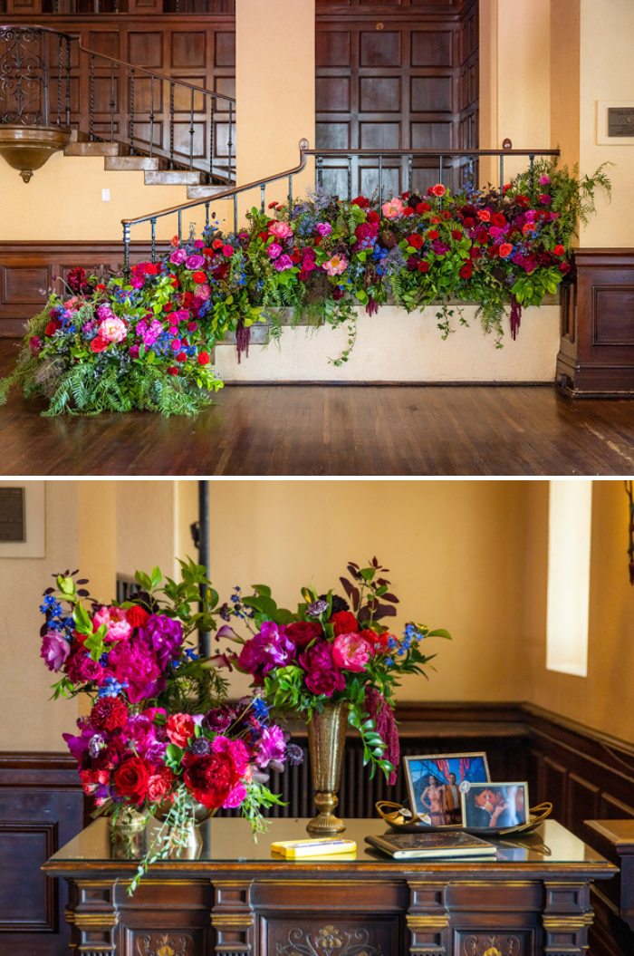 A large scale floral installation on the staircase at The Ebell of Los Angeles features peonies and garden roses in bold jewel tones. In the second image- a bold welcome arrangement greets guests next to photos of the couple. 