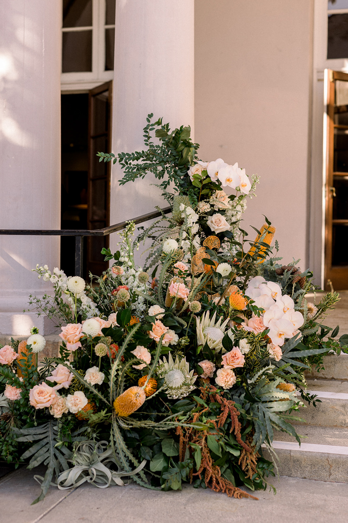 Incredible, whimsical and magical ceremony floral installation by Los Angeles Floral Designer, Winston & Main, for this California wedding at The Ebell of Los Angeles contains King Protea, Banksia, Air Plants, Orchids, Dahlias, Scabiosa, Amaranthus, Protea, Rose and more! 