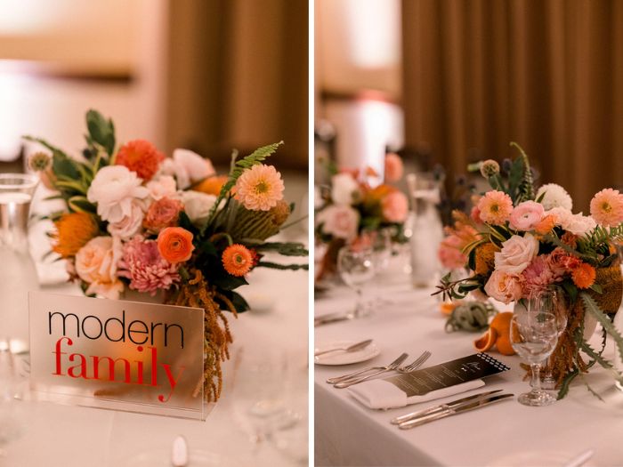 The wedding reception details include acrylic table numbers showing the couples favorite TV shows, and large citrus-hued centerpieces full of dahlias and garden roses.
